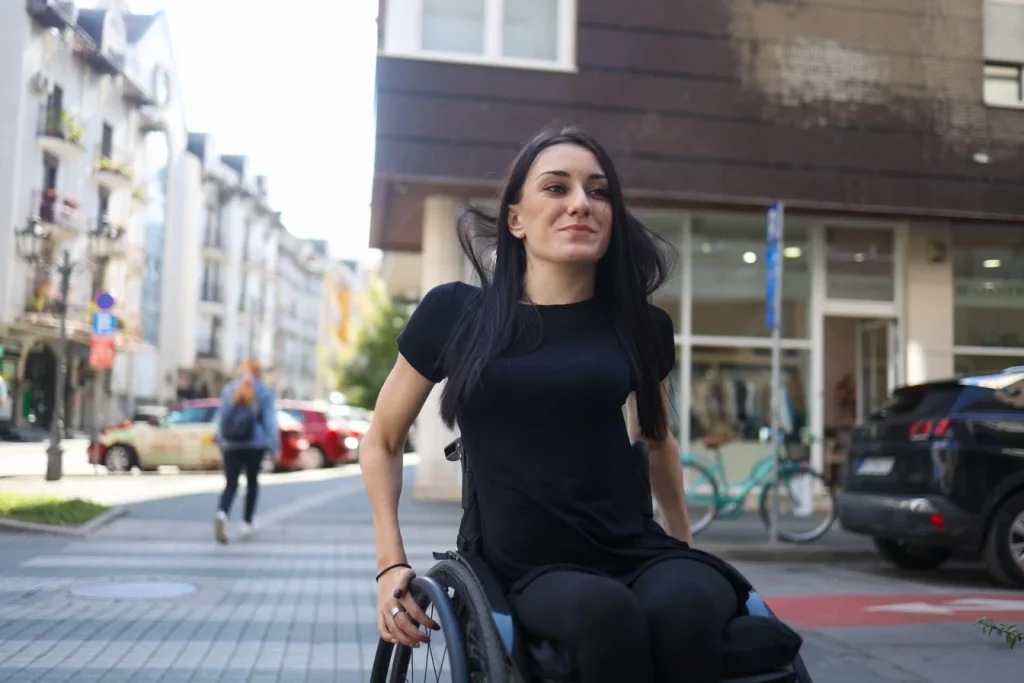 Disabled woman in wheelchair crossing footpath and smiling
