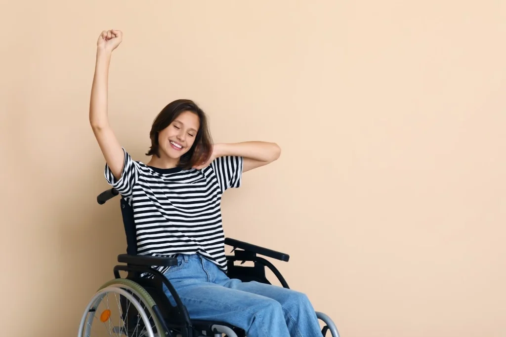 Disabled woman in wheelchair smiling with one arm in the air